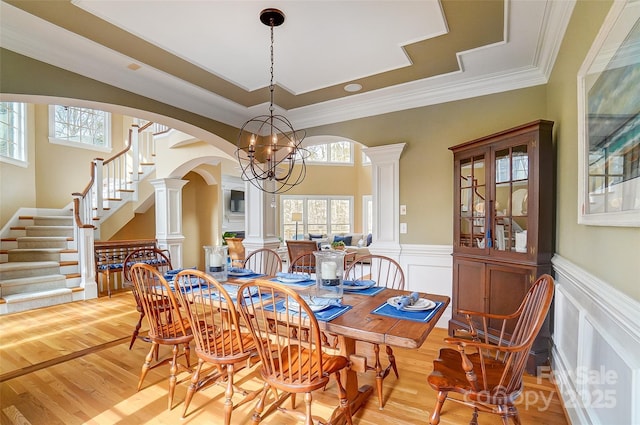 dining space with crown molding, plenty of natural light, light hardwood / wood-style flooring, and ornate columns