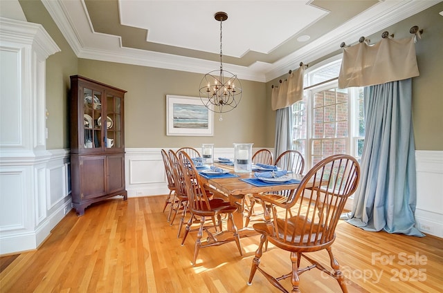 dining room with a notable chandelier, crown molding, light hardwood / wood-style floors, and a raised ceiling