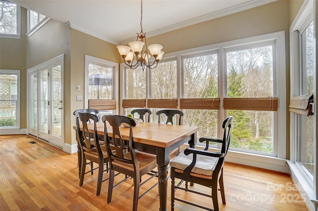 dining area with crown molding, light wood-type flooring, and a notable chandelier