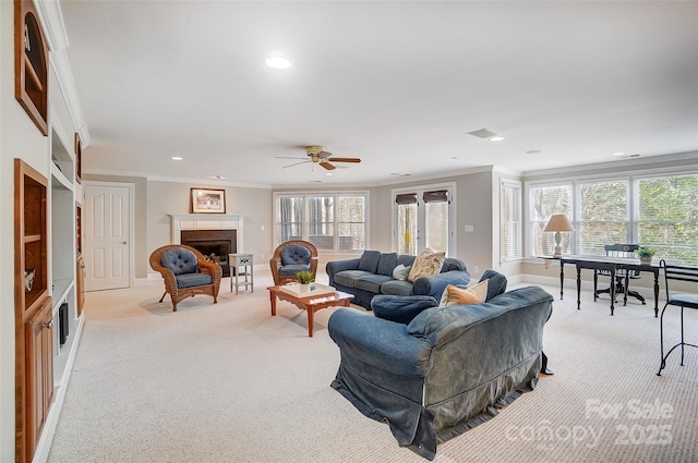 carpeted living room with ceiling fan and ornamental molding