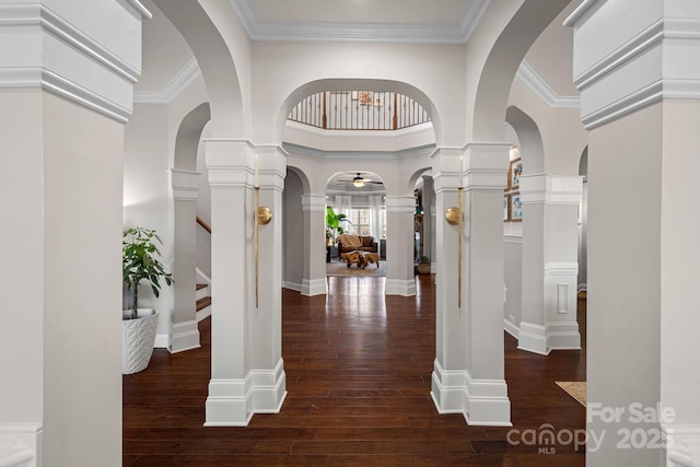 interior space with decorative columns, crown molding, dark wood-type flooring, and a high ceiling