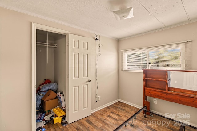 bedroom with hardwood / wood-style flooring, a closet, and ornamental molding