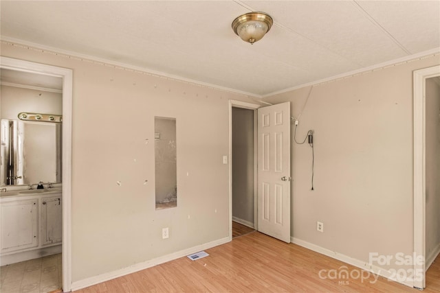 unfurnished bedroom with ensuite bathroom, light hardwood / wood-style floors, crown molding, and sink