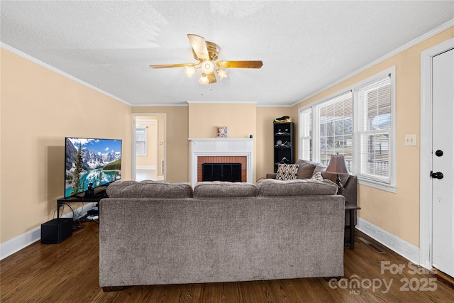 living room with a textured ceiling, a fireplace, ornamental molding, ceiling fan, and dark hardwood / wood-style flooring