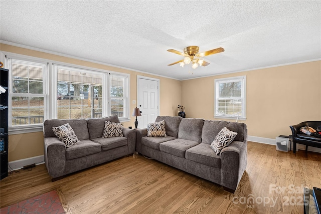 living room with light wood-type flooring, ornamental molding, a textured ceiling, and ceiling fan