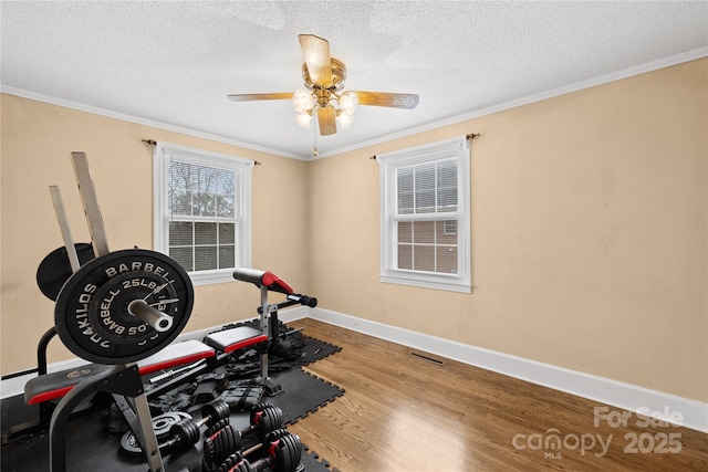 exercise area featuring ornamental molding, ceiling fan, a textured ceiling, and hardwood / wood-style flooring