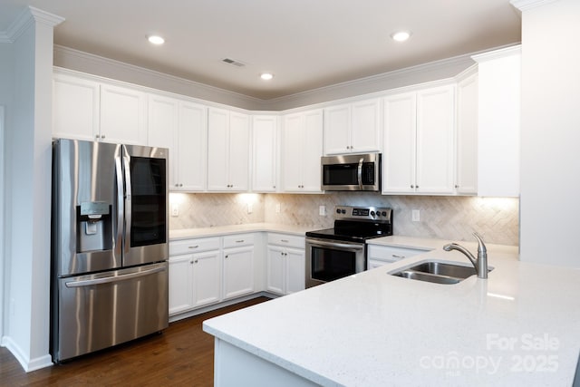 kitchen with white cabinets, appliances with stainless steel finishes, sink, backsplash, and kitchen peninsula