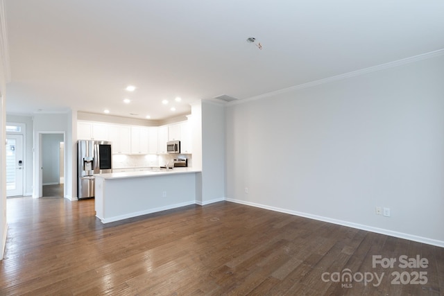 kitchen featuring kitchen peninsula, decorative backsplash, crown molding, stainless steel appliances, and white cabinets