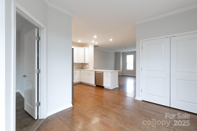 kitchen with dishwasher, white cabinetry, backsplash, kitchen peninsula, and crown molding