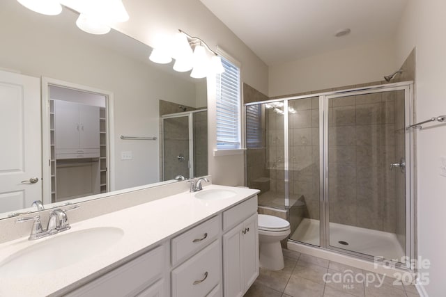 bathroom featuring toilet, vanity, a shower with door, and tile patterned floors