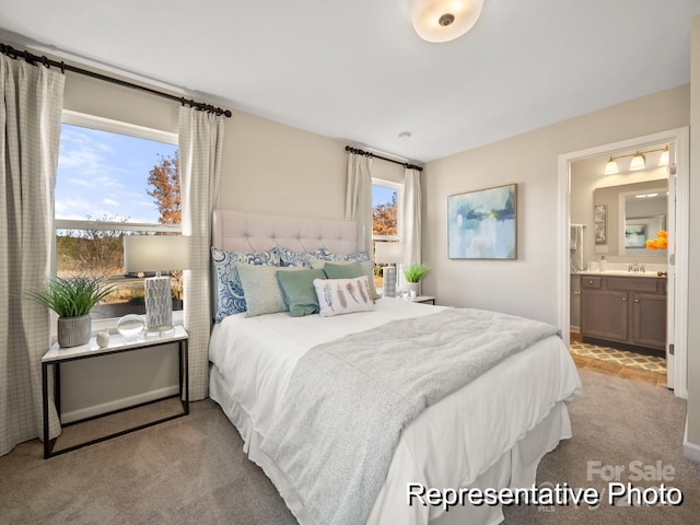 bedroom featuring light colored carpet, sink, and ensuite bath