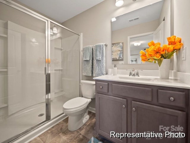 bathroom with vanity, toilet, and a shower with door