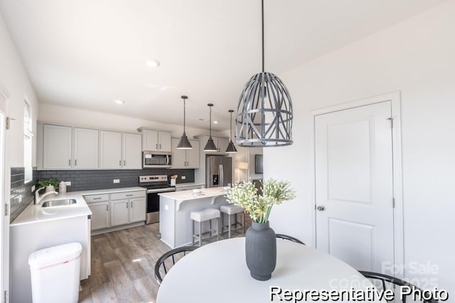 205 Cliffwood St NW Unit Unitb-2, Concord, NC 28027 - kitchen featuring stainless steel appliances, a breakfast bar area, decorative backsplash, light countertops, and light wood-type flooring