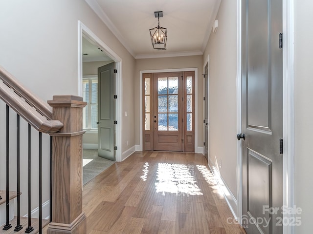 entrance foyer with light wood finished floors, stairway, an inviting chandelier, ornamental molding, and baseboards