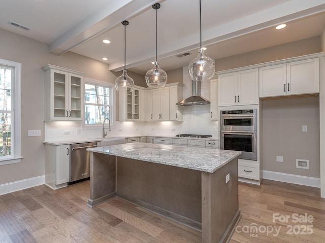 kitchen featuring visible vents, beamed ceiling, stainless steel appliances, wall chimney range hood, and backsplash