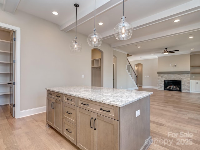 kitchen with light wood-style floors, baseboards, arched walkways, and beam ceiling