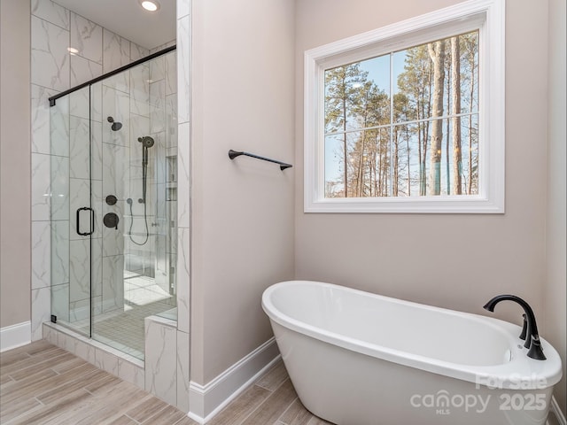 bathroom featuring a stall shower, a freestanding tub, and wood tiled floor