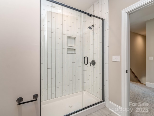 full bath with a shower stall and baseboards