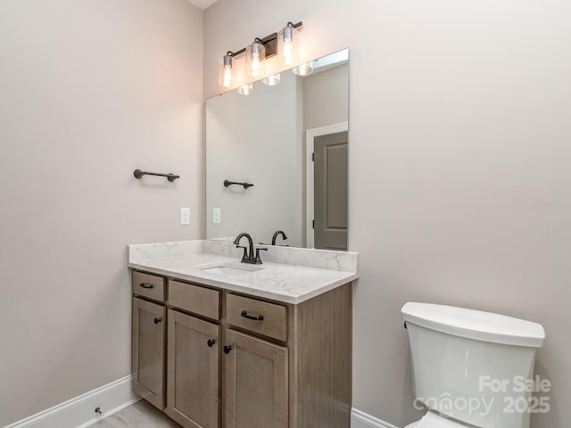 bathroom with vanity, toilet, and baseboards