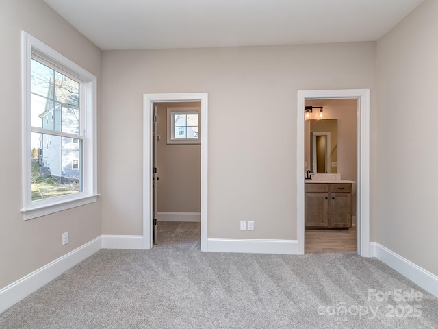 spare room with baseboards, a wealth of natural light, and light colored carpet