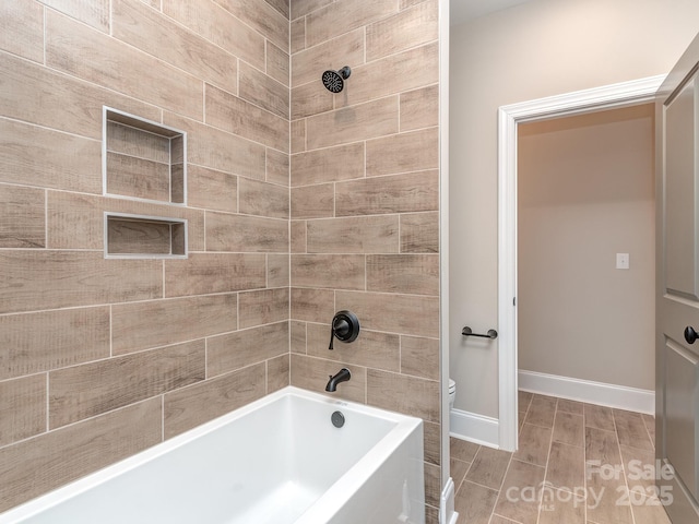 bathroom with wood tiled floor, bathtub / shower combination, baseboards, and toilet