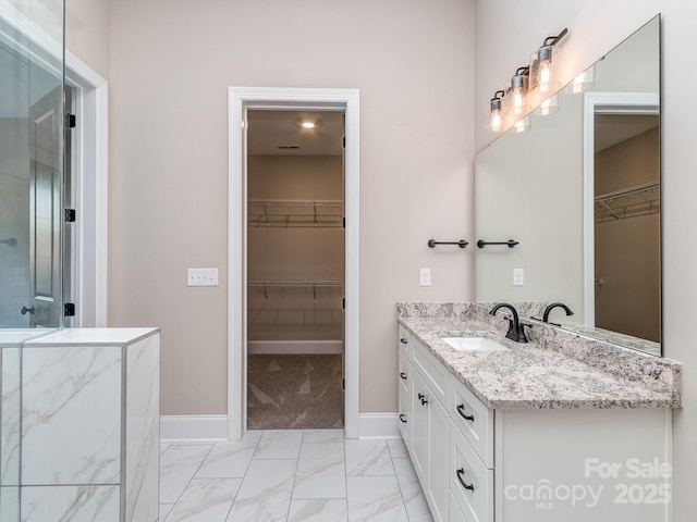 full bathroom featuring baseboards, a shower with door, marble finish floor, a walk in closet, and vanity