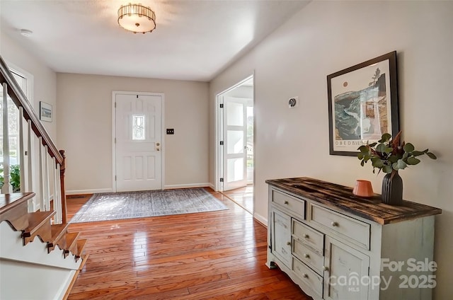 foyer featuring stairway, baseboards, and light wood finished floors