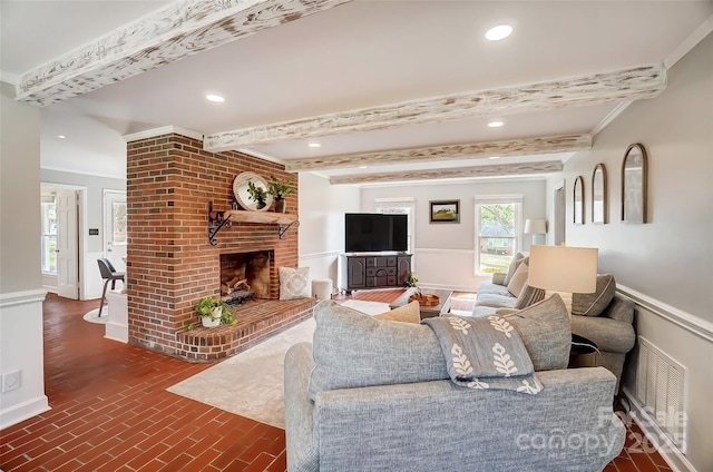 living area featuring a brick fireplace, beamed ceiling, recessed lighting, and brick floor