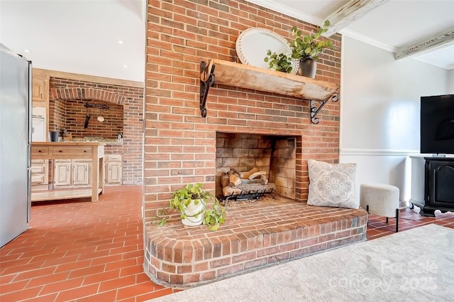 living room with crown molding, beamed ceiling, a fireplace, and brick floor