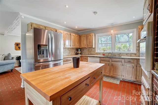 kitchen with backsplash, crown molding, butcher block counters, appliances with stainless steel finishes, and a sink