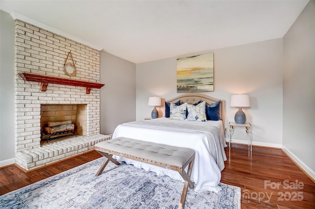 bedroom featuring a brick fireplace, wood finished floors, and baseboards