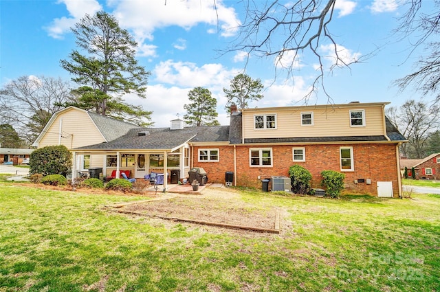 rear view of house with a patio area, central AC unit, a yard, and brick siding