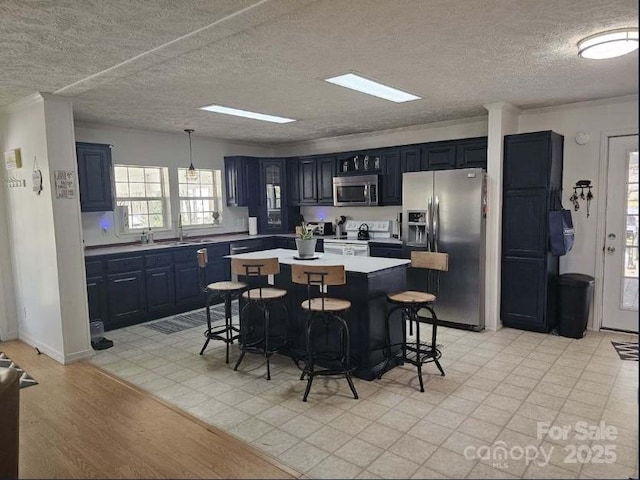 kitchen with sink, stainless steel appliances, a kitchen breakfast bar, a kitchen island, and decorative light fixtures