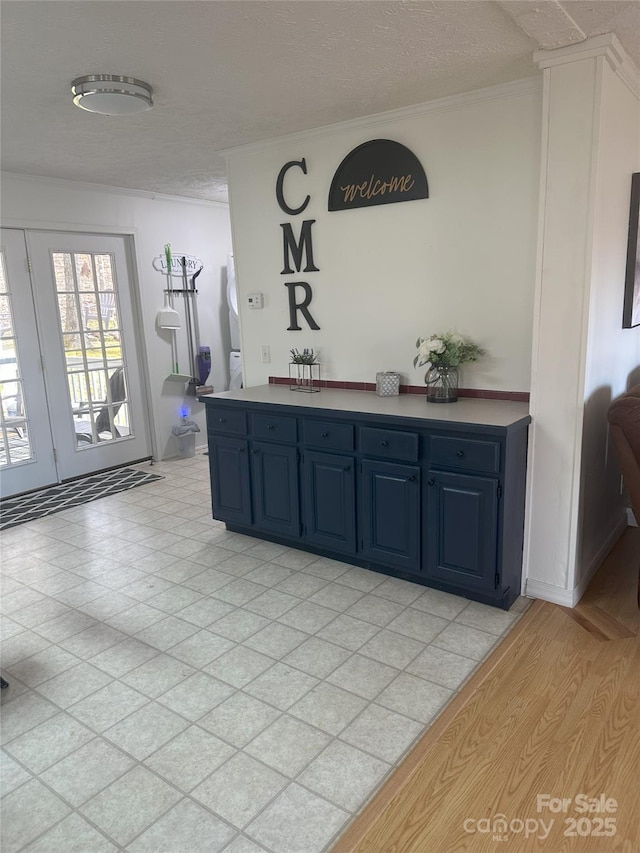 interior space featuring ornamental molding, a textured ceiling, and blue cabinets