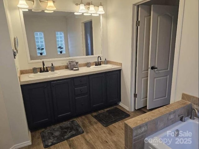 bathroom with vanity, a bath, and wood-type flooring