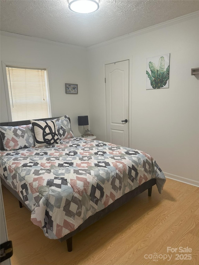 bedroom featuring light hardwood / wood-style flooring, ornamental molding, and a textured ceiling