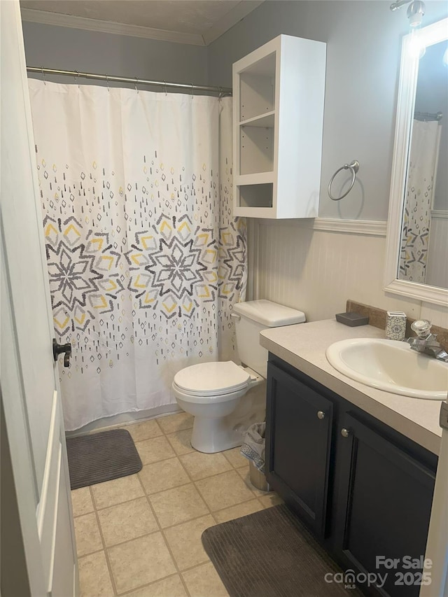 bathroom with tile patterned flooring, crown molding, vanity, and toilet