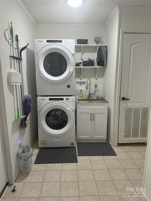 washroom featuring stacked washer and dryer, sink, cabinets, a textured ceiling, and ornamental molding