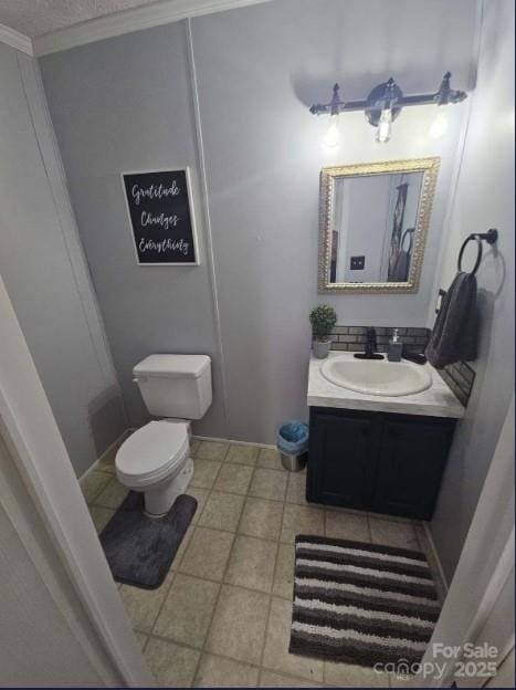 bathroom featuring vanity, ornamental molding, a textured ceiling, tile patterned floors, and toilet