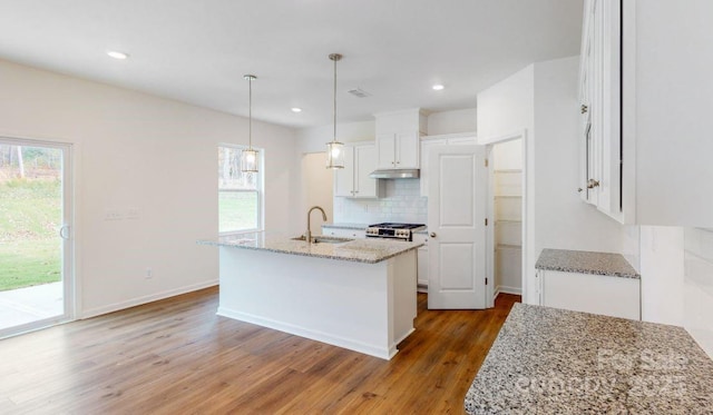 kitchen featuring a kitchen island with sink, dark wood-type flooring, sink, decorative light fixtures, and white cabinetry