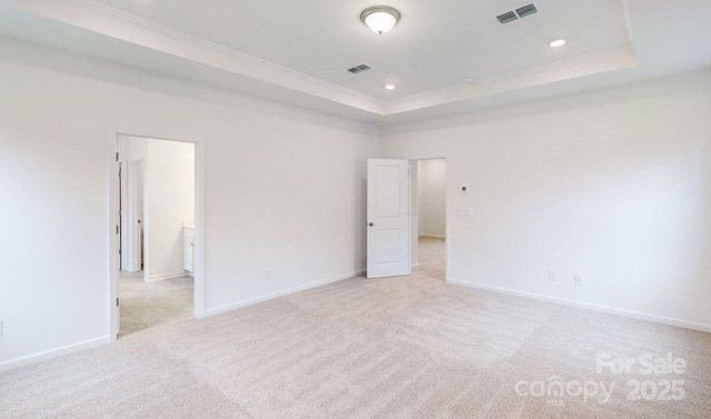 unfurnished bedroom featuring light carpet, a raised ceiling, ensuite bath, and crown molding