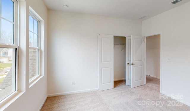 unfurnished bedroom featuring light carpet, multiple windows, and a closet