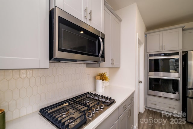 kitchen with tasteful backsplash, dark hardwood / wood-style flooring, stainless steel appliances, and white cabinetry