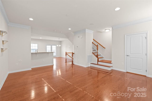 interior space with ornamental molding, a chandelier, and hardwood / wood-style floors