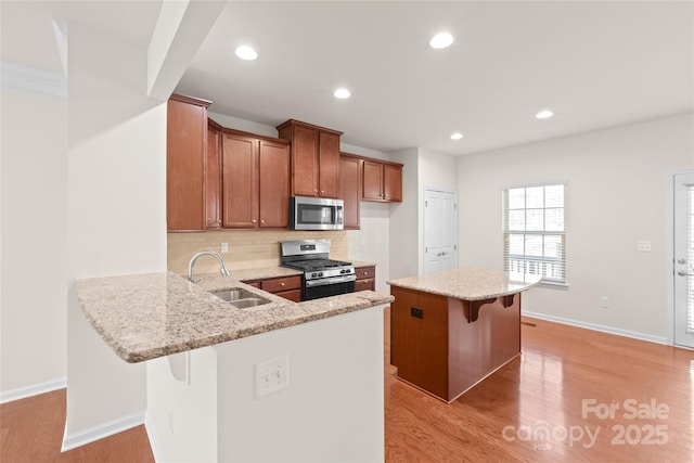 kitchen featuring appliances with stainless steel finishes, a breakfast bar, sink, and kitchen peninsula