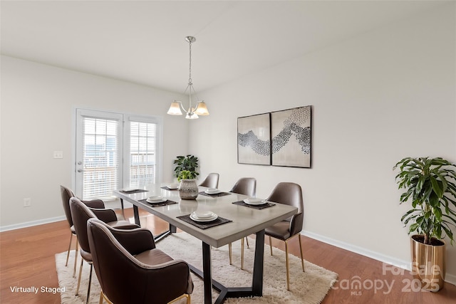 dining space featuring hardwood / wood-style floors and a chandelier