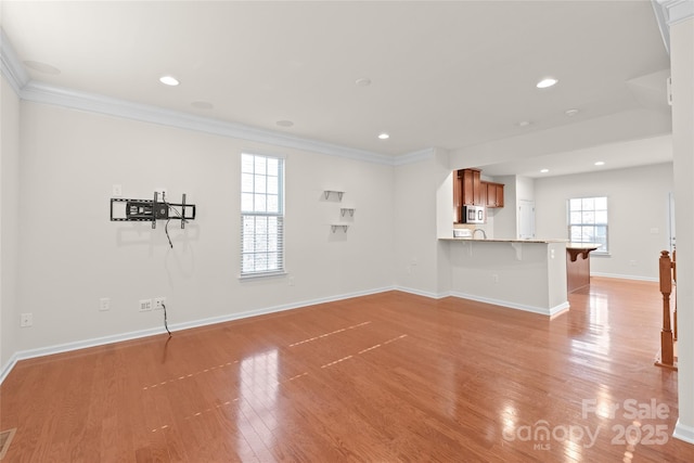 unfurnished living room featuring ornamental molding and light wood-type flooring