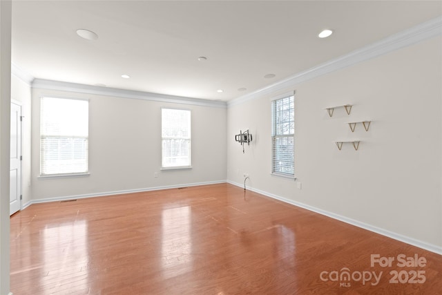 spare room featuring ornamental molding, a healthy amount of sunlight, and light hardwood / wood-style floors