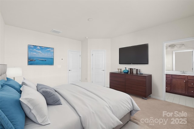 carpeted bedroom featuring ensuite bathroom and sink