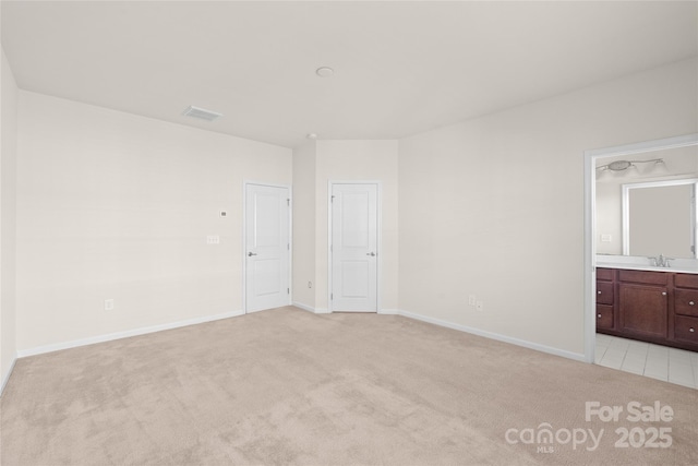 unfurnished bedroom featuring sink, light colored carpet, and connected bathroom